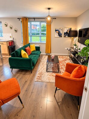 A modern living room with a green sofa, orange armchair, and a coffee table.
