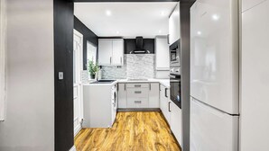 Una cocina moderna con armarios blancos, un refrigerador Bosch y piso de madera.