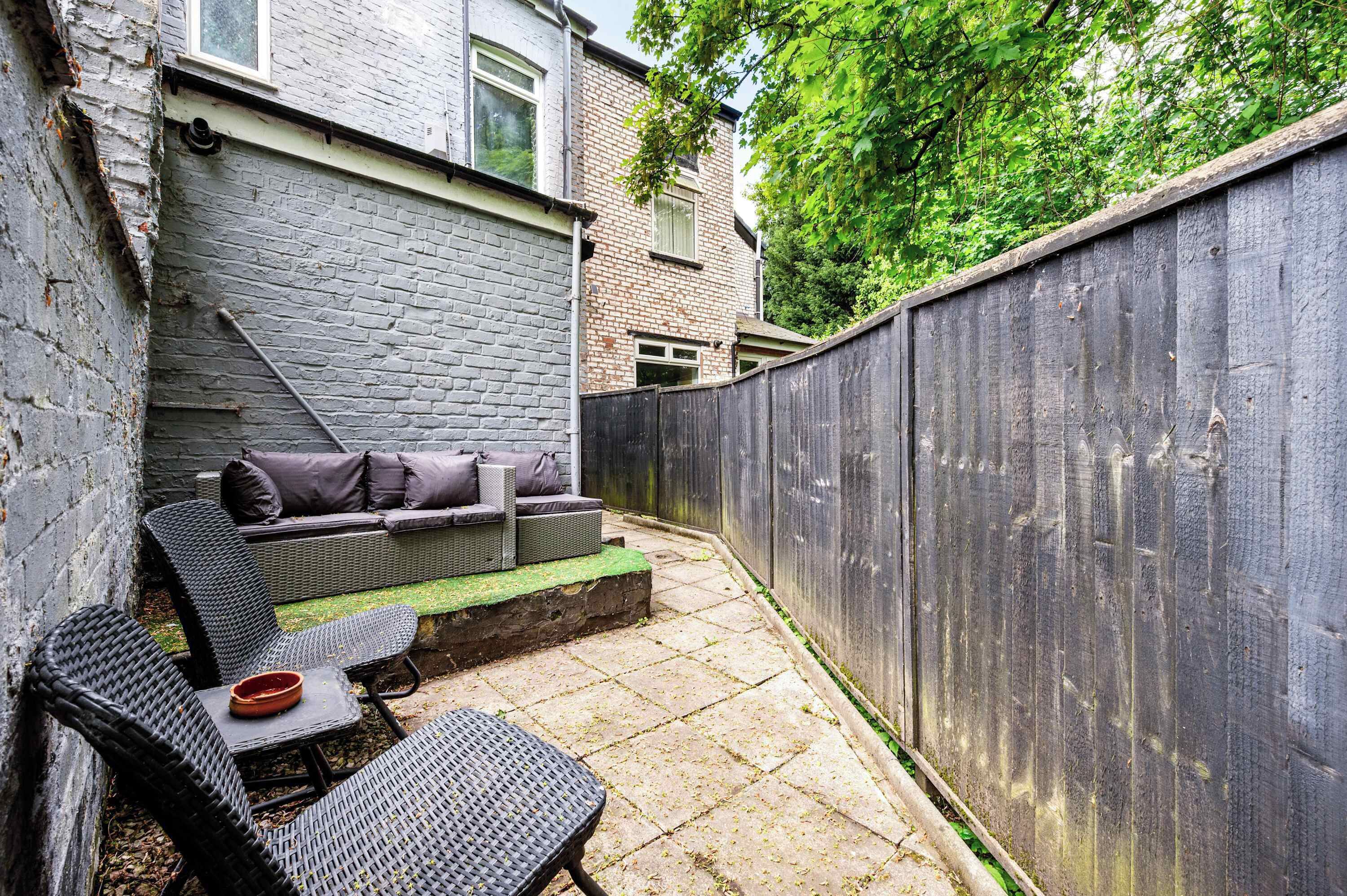 A patio with wicker furniture, a small table, and a brick wall.