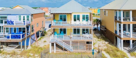 A beachfront property with multiple levels, outdoor seating, and a staircase leading to the upper floors.