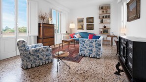 Un soggiorno con un divano blu, due poltrone, un mobile in legno e una libreria.