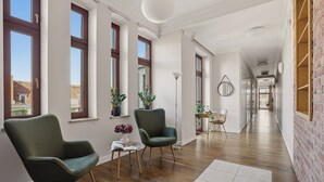 A spacious hallway with wooden flooring, large windows, and a brick wall. - AS HOME Apartamenty Rynek 50 (Wroclaw)