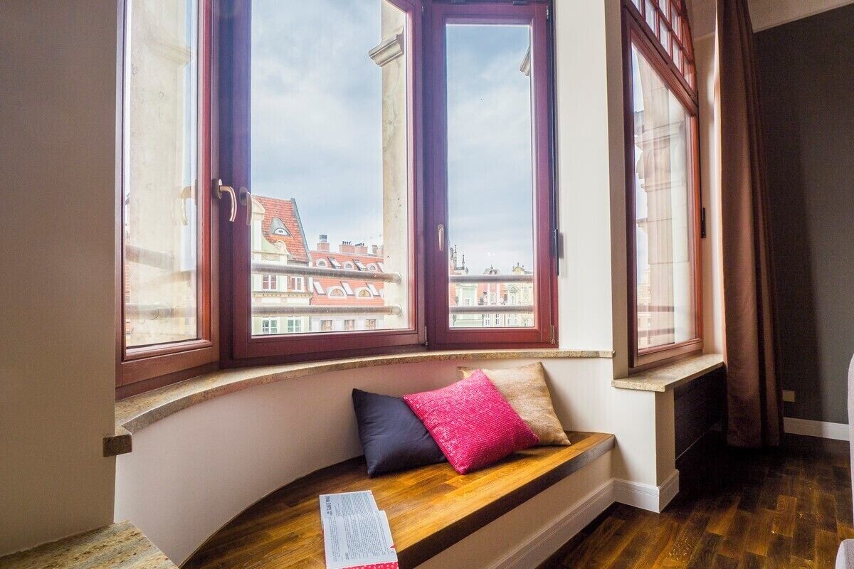A room with a built-in bench by a large window overlooking a cityscape.
