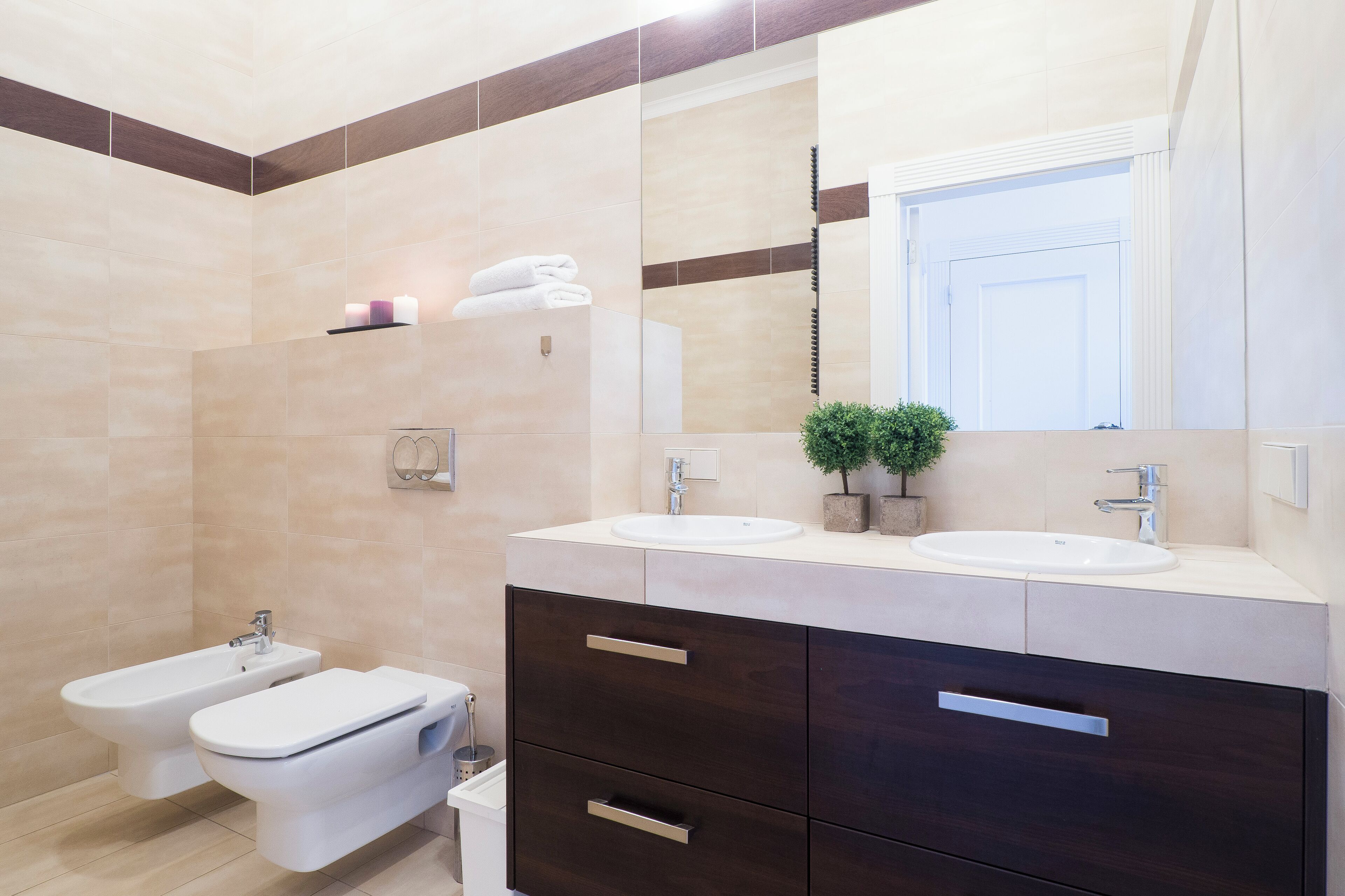 A modern bathroom with two sinks, a bidet, and a large mirror.