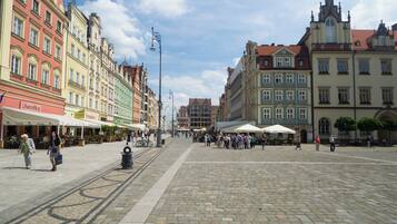 A cobblestone square with historic buildings, outdoor cafes, and a clear sky.