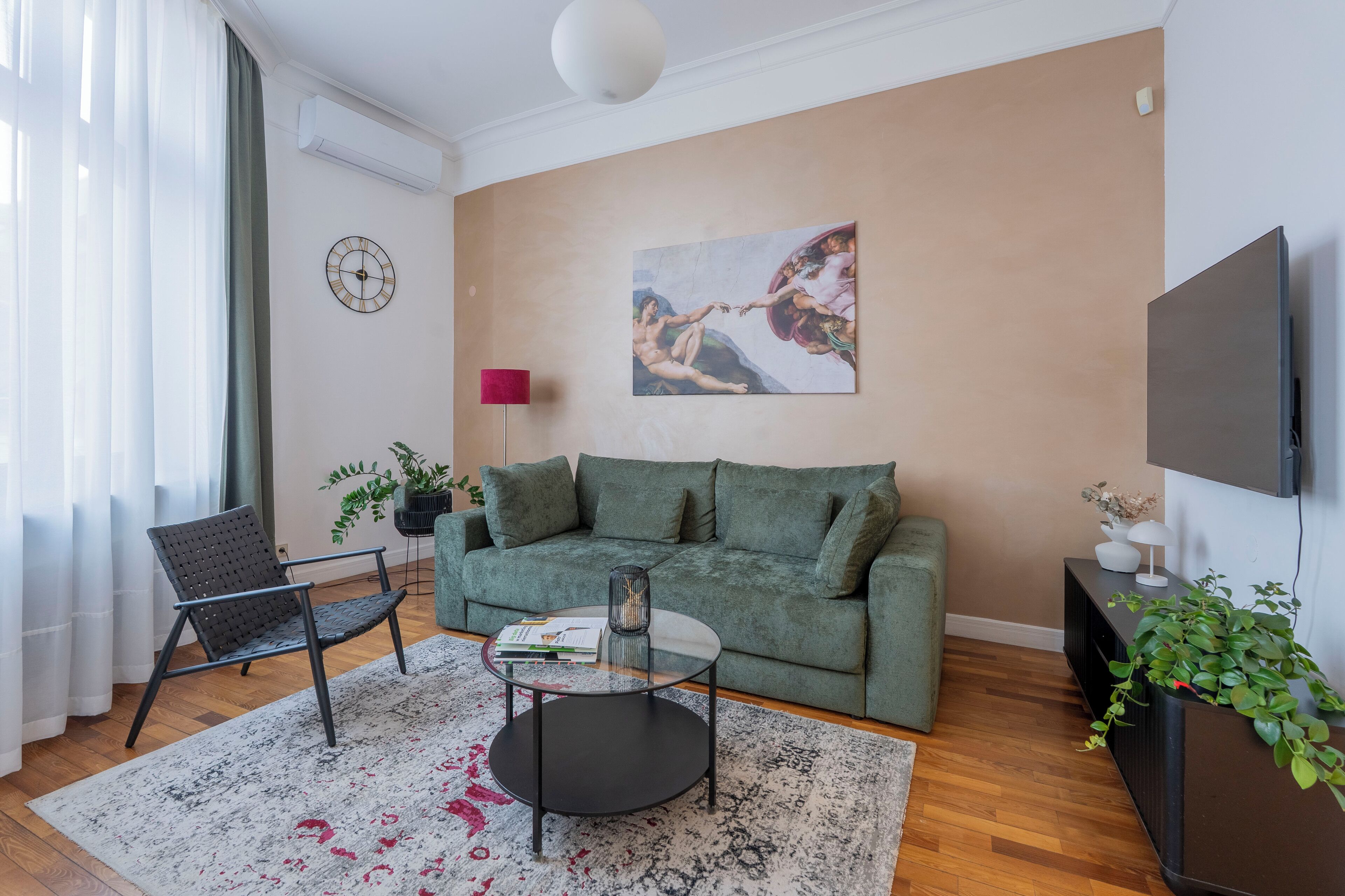 A modern living room with a green sofa, a round coffee table, a black chair, and a large painting on the wall.