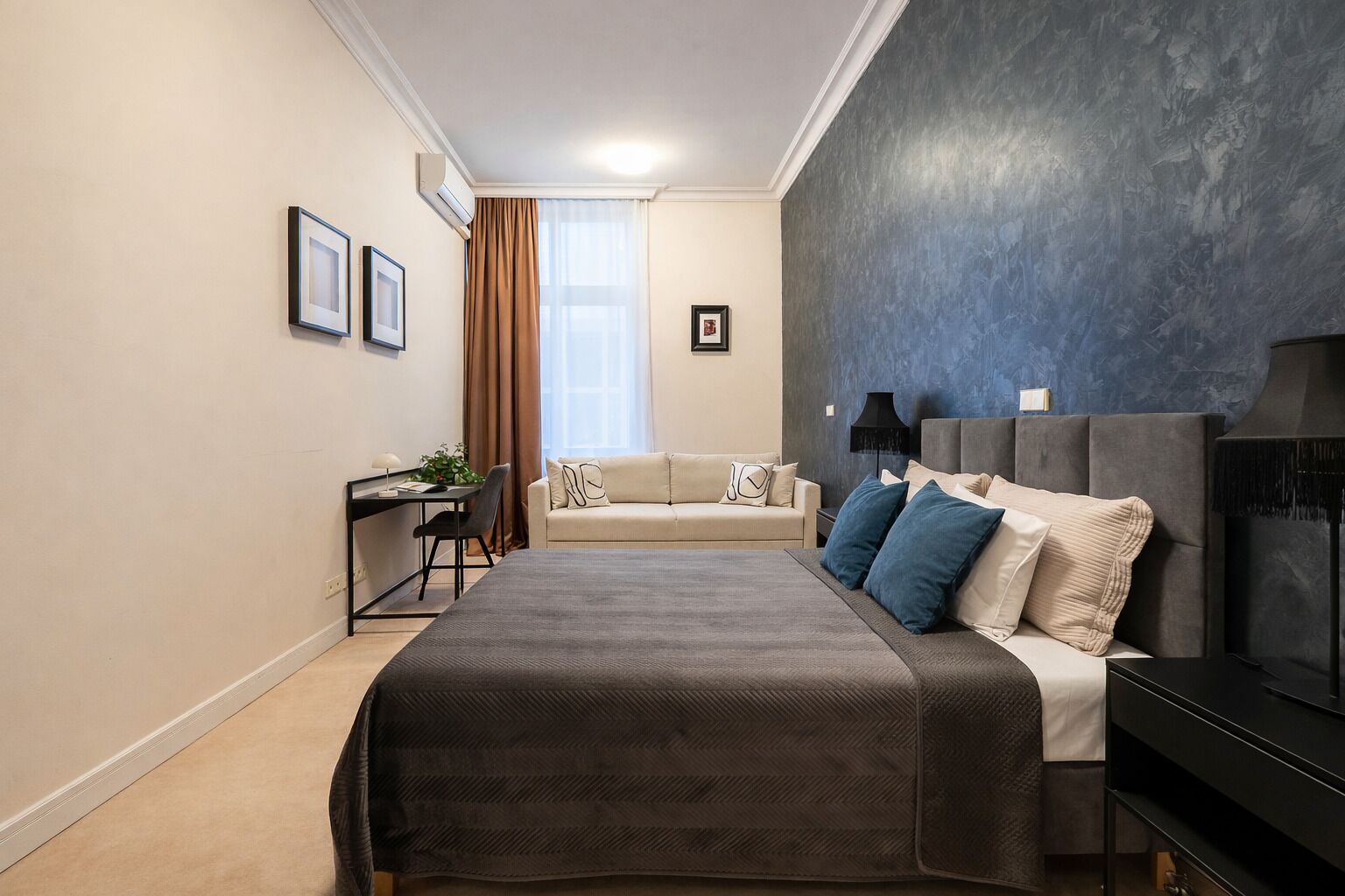 Un dormitorio moderno con una cama grande, un escritorio y un sofá.