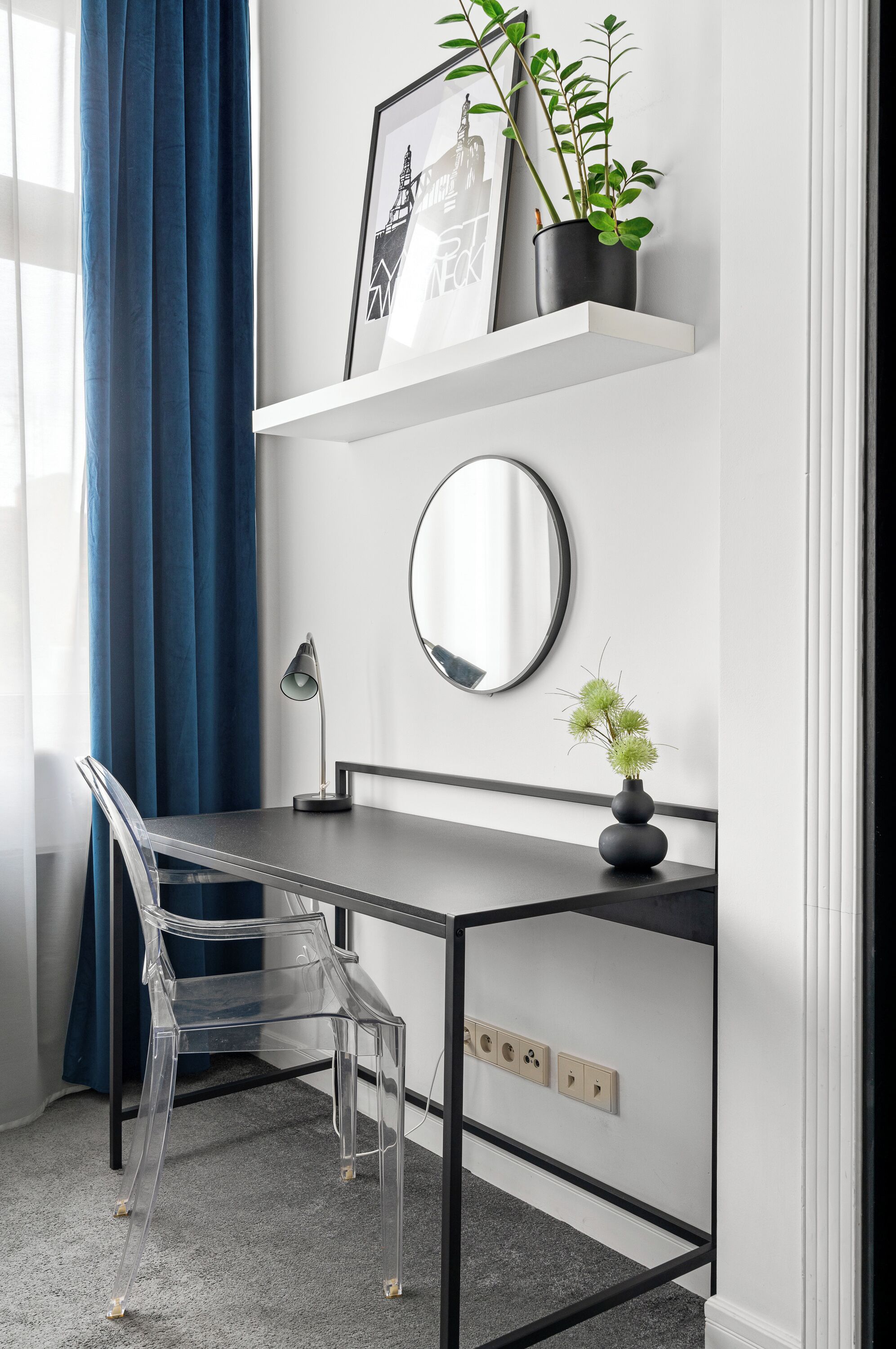 Un espace de travail moderne comprenant un bureau, une chaise et une étagère murale agrémentée de plantes et d’un tableau.
