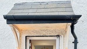 A doorway leading into a room with a table and chairs, a hanging light fixture, and a wall-mounted light. - Pengam House (Cardiff)