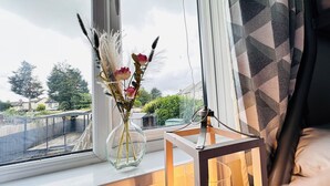 A window with a vase of flowers and a candle holder on a windowsill. - Pengam House (Cardiff)