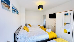 A bedroom with two beds, a mirror, a TV, and artwork on the wall. - Pengam House (Cardiff)