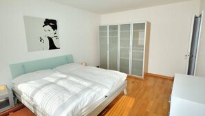 A bedroom with a bed, a wardrobe, and a bedside table. - Tranquil Seafront Escape (Zürich)
