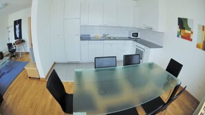 A modern kitchen with white cabinets, a glass dining table, and black chairs. - Tranquil Seafront Escape (Zürich)