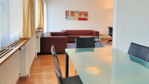 A modern living room with a glass-top dining table, a sofa, and a coffee table. - Tranquil Seafront Escape (Zürich)