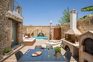 A stone building with a pool, outdoor seating, and a brick oven.