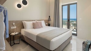 A modern bedroom with a large bed, a bedside table, a hanging light, and a view of the ocean through a sliding door. - GG Villas Falassarna (Chania)