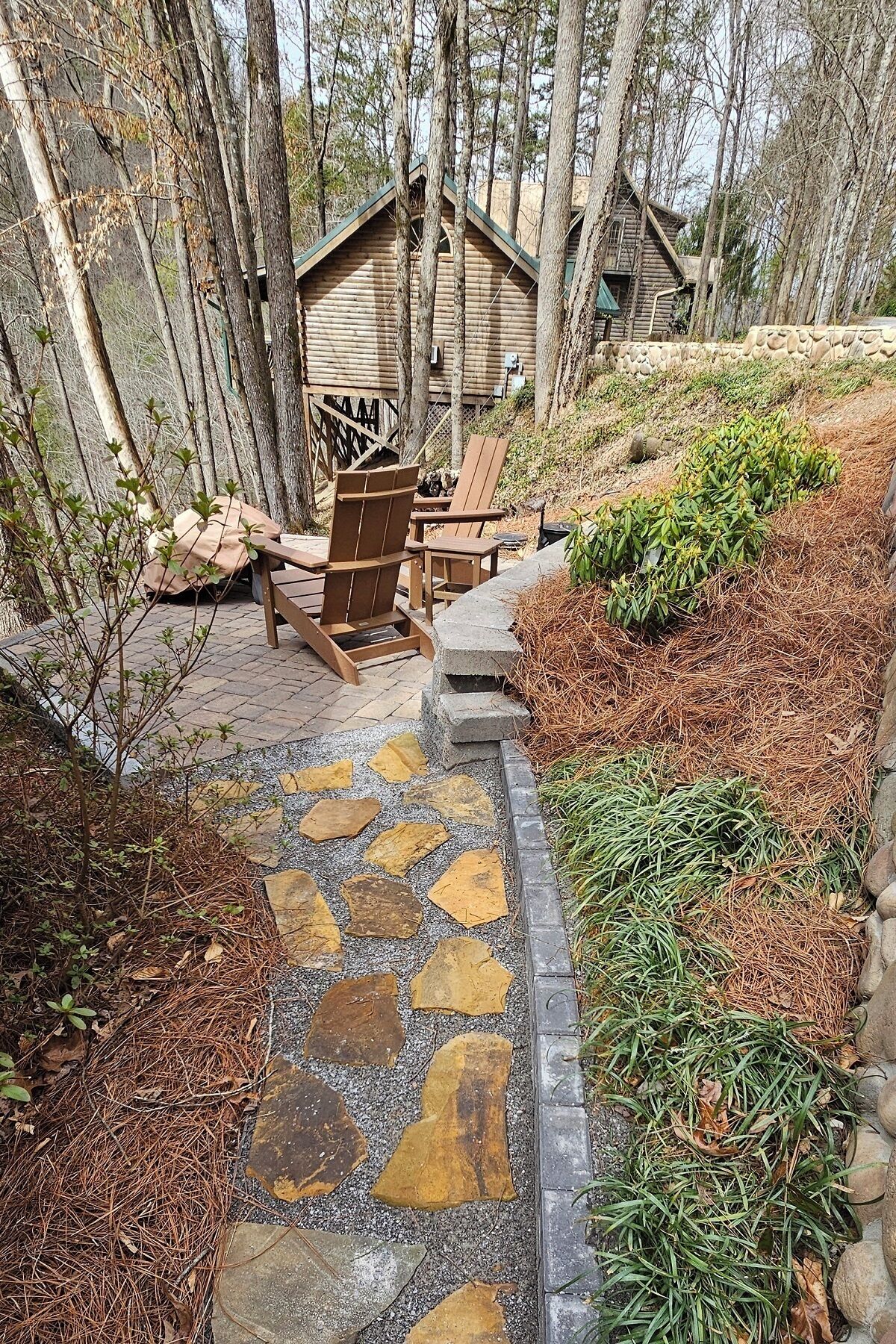 Una cabaña de madera con un camino de piedra que lleva a un área de estar al aire libre.