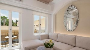 A room with a beige sofa, a wooden coffee table with a plant, and a large ornate mirror on the wall. - Il Campanile Suite for Two (Crete)