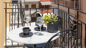 A balcony with a round table, two wine glasses, a cup, and a potted plant. - Il Campanile Suite for Two (Crete)