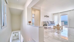 A spacious living area with a balcony, a sofa, and a coffee table. - Hannah Villa Stalos: spacious, quiet villa w/sea and mountain view (Chania)