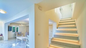 A spacious living area with a marble floor, a staircase with built-in lighting, and a chandelier. - Hannah Villa Stalos: spacious, quiet villa w/sea and mountain view (Chania)