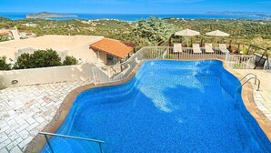A swimming pool with a view of the sea and hills.