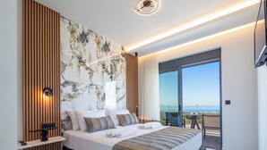 Un dormitorio moderno con una cama grande, una pared de mármol, un panel de madera, una lámpara de techo y un balcón con vistas.