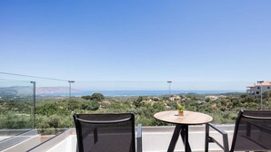 A balcony with two chairs and a small round table, overlooking a scenic landscape with hills and a distant view of the sea. - Horizon West Villa │Private Pool, Secluded Luxury Modern Villa (Chania)