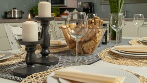 Una mesa de comedor adornada con velas, pan, copas de vino y un bol de pan.