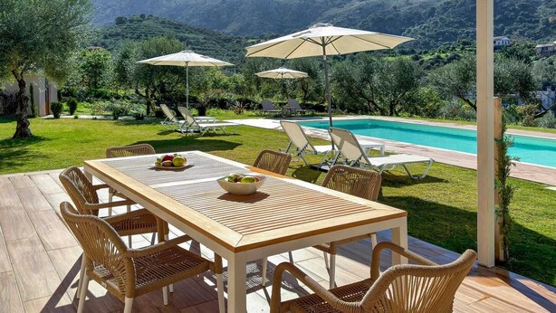 A patio with a pool, wicker furniture, and umbrellas. - Villa Adam: Tranquility and Luxury with a Poolside View (Crete)
