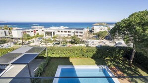 A modern hotel with a pool, a view of the sea, and solar panels on the roof. - Modern villa w/pool, near beach & city centre (Crete)