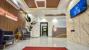 A modern hotel lobby with a reception desk, seating area, and a TV screen. - Twinny Hotels & Suites (Lagos)