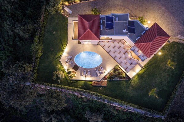 An aerial view of a resort with a swimming pool, sun loungers, and a covered patio area.