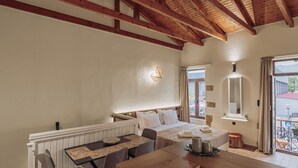 A cozy room with a wooden ceiling, a bed with white linens, a dining table with chairs, and a window with curtains. - Immerse yourself in Santa Lucia, a cozy, modern studio (Chania)