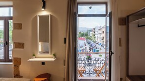 A room with a large window, a mirror, a small plant, and a balcony with a table and chairs. - Immerse yourself in Santa Lucia, a cozy, modern studio (Chania)