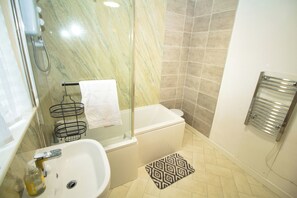 Cottage | Badkamer | Een bad/douchecombinatie, een diep bad, een haardroger, handdoeken