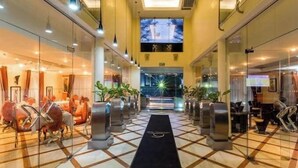 A hotel lobby with a checkered floor, glass walls, and a central black carpet leading to an elevator. - Morning Side Boutique Hotel and Suites (Lagos)