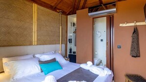 Una cama bien hecha con sábanas blancas y un almohárraga color turquesa, un cabecero de madera y una mesita de noche con una toalla.