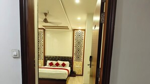 A hotel room with a bed, a ceiling fan, and a decorative wall panel. - Hotel Ishaan Residency MGM CLUB (New Delhi)