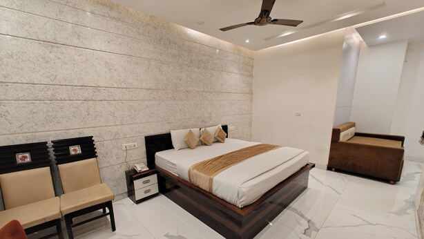 A modern bedroom with a bed, bedside tables, a chair, and a sofa. - Hotel Ishaan Residency MGM CLUB (New Delhi)