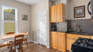 Una cocina con armarios de madera, estufa, fregadero y una mesa de comedor con sillas.