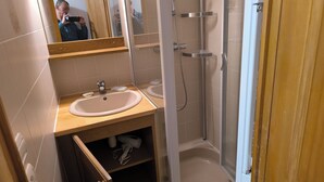 A bathroom with a wooden vanity, a sink, a mirror, and a glass-enclosed shower. - Apartment foreclosures (Villard-sur-Doron)