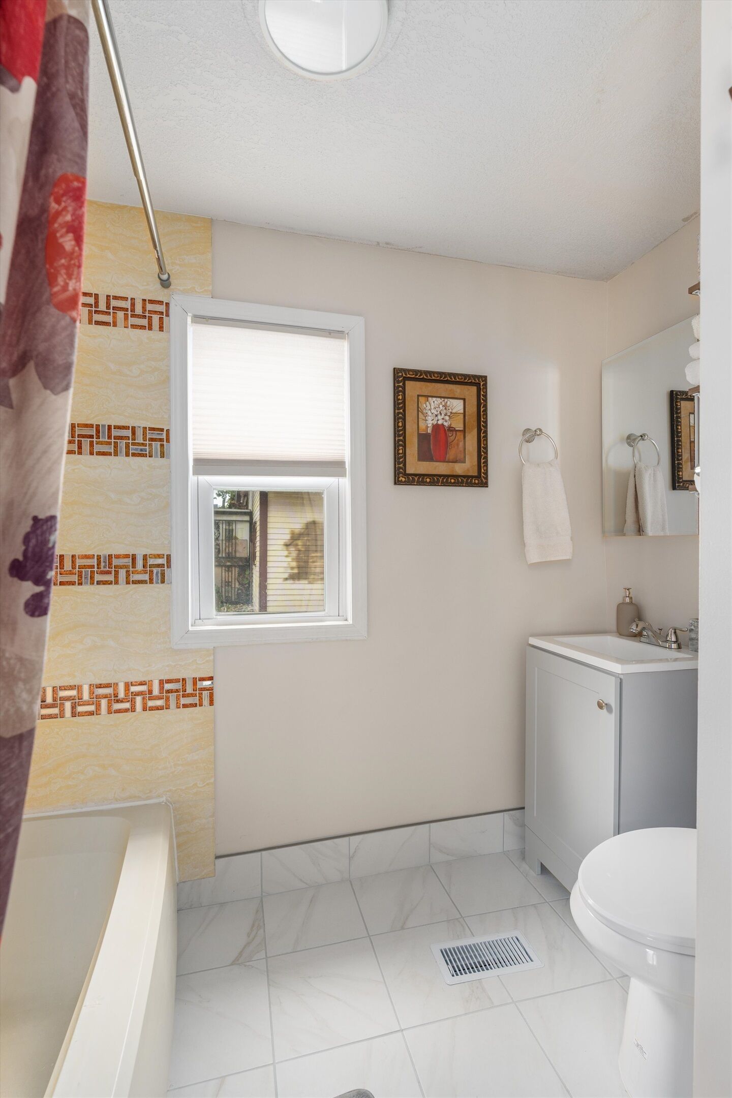 Un baño con ventana, lavamanos, inodoro y cortina de ducha.
