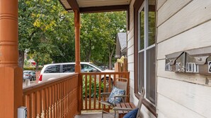 Une véranda couverte avec une balustrade en bois, un banc et une chaise avec un coussin.