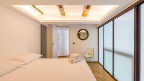 A modern hotel room with a large bed, a skylight, a mirror, and a view through floor-to-ceiling glass windows. - Design Studio Duplex at National Museum (Naples)