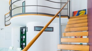 A modern spiral staircase with wooden steps and metal railings, leading to an upper floor. - Design Studio Duplex at National Museum (Naples)