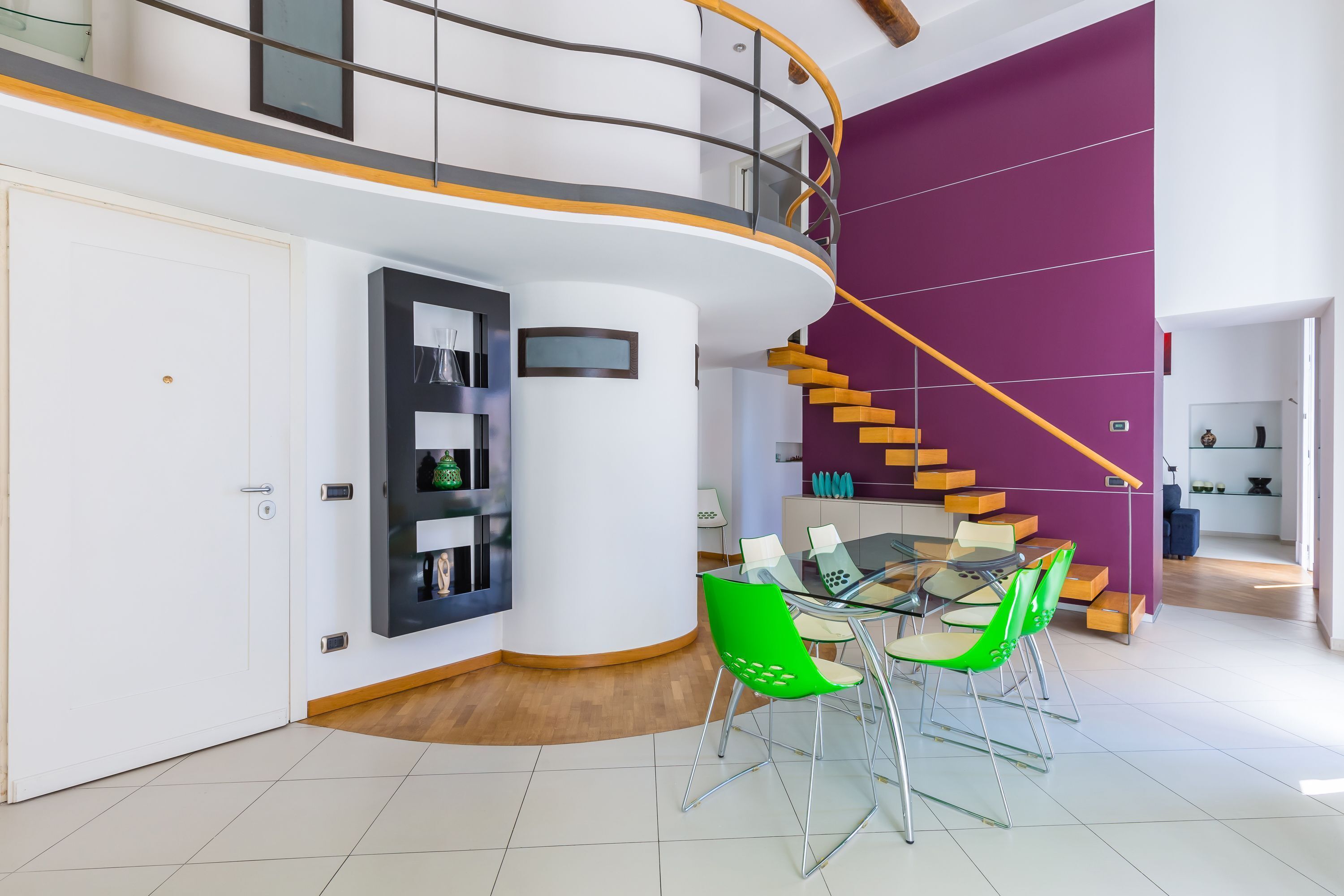 A modern interior with a dining area, a staircase, and a built-in bookshelf.
