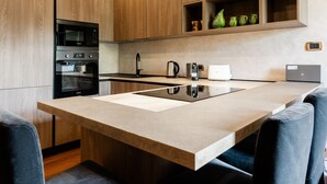 Una cocina moderna con armarios de madera, microondas integrado, horno y una isla grande con fregadero.