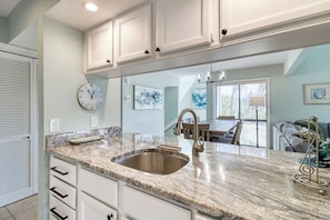 A kitchen with a double sink, white cabinets, and a clock on the wall.