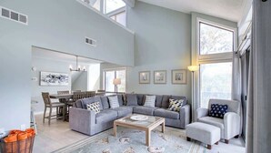 A spacious living room with a gray sectional sofa, a coffee table, and a patterned rug.